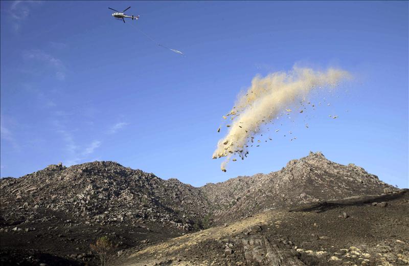 Un helicóptero arroja balas de paja de trigo sobre el campo. EFE/Lavandeira jr