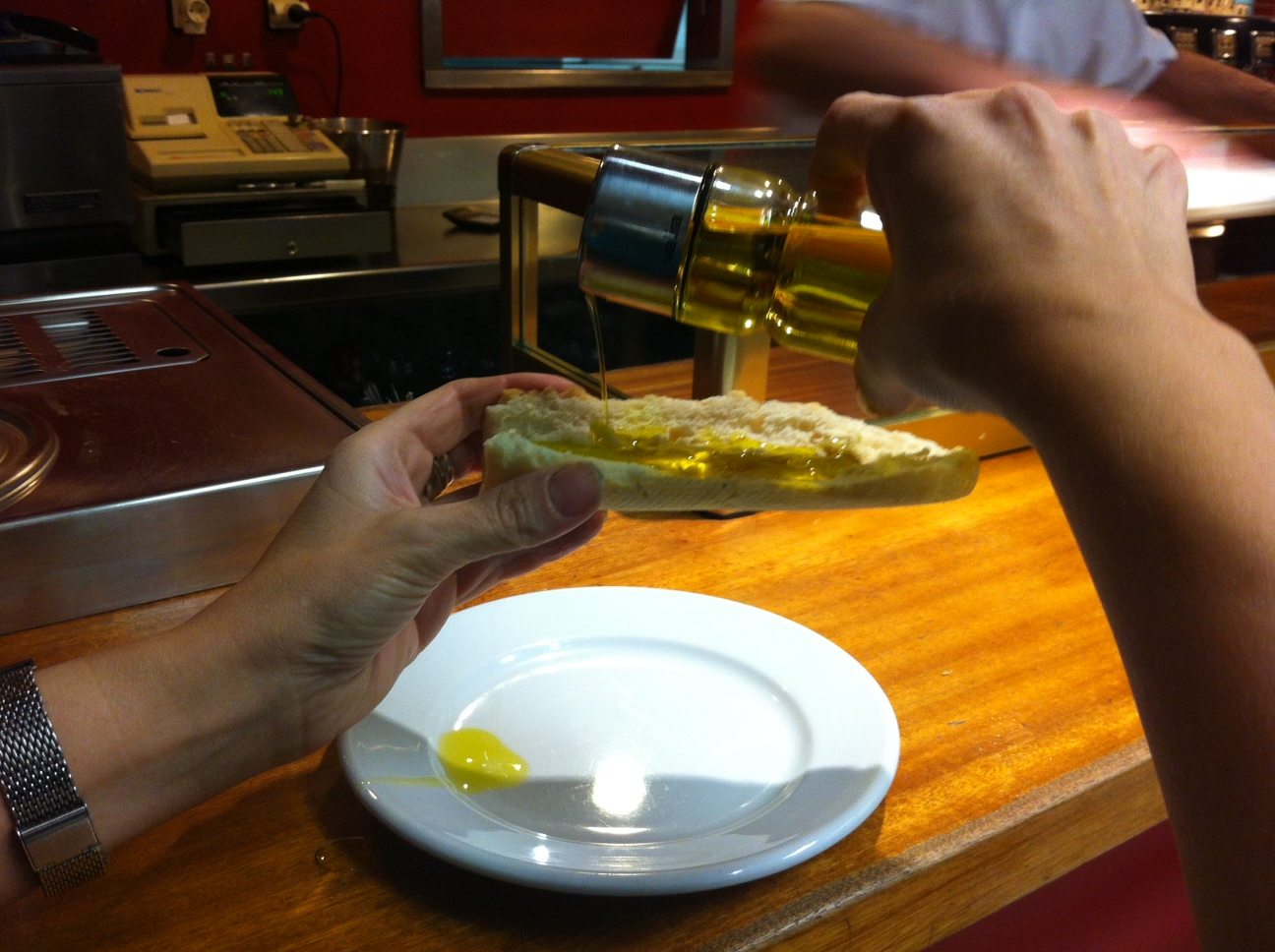 Un comensal extiende aceite de oliva sobre una tostada, en imagen de archivo. Foto: J.J.RÍOS