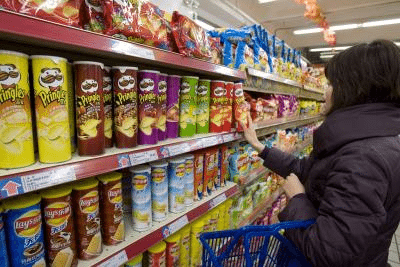 Una consumidora escoge un paquete de patatas fritas en un supermercado. Foto: Archivo EFE / Diego Azubel.