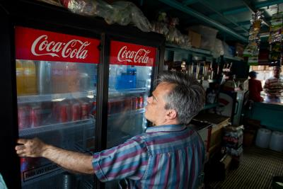 Un hombre cierra una nevera con latas de de Coca-Cola. EFE/MIGUEL GUTIÉRREZ