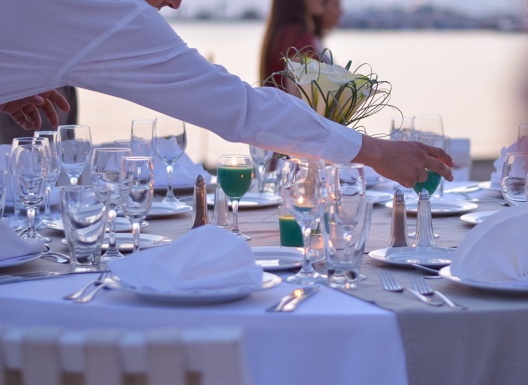 Imagen de una mesa donde un camarero prepara un servicio de catering