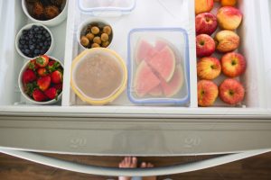 Imagen de fruta peleda y cortada en varios recipientes en el interior de un frigorífico.