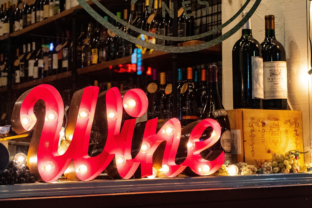 Un letrero con la palabra "vino" en inglés luce en un bar. Efeagro/Pexels