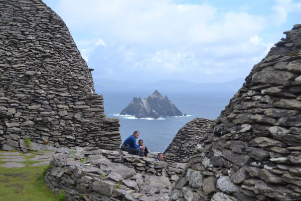 Un par de turistas descansa de la larga ascensión y contempla el espectacular paisaje entre las construcciones del monasterio. Al fondo, la isla Pequeña Skellig, y más allá, la costa irlandesa. Foto: Rafael Cañas.